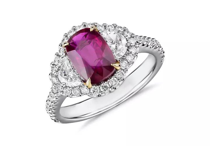 A cushion cut ruby engagement ring accented by half moon diamond and halo setting